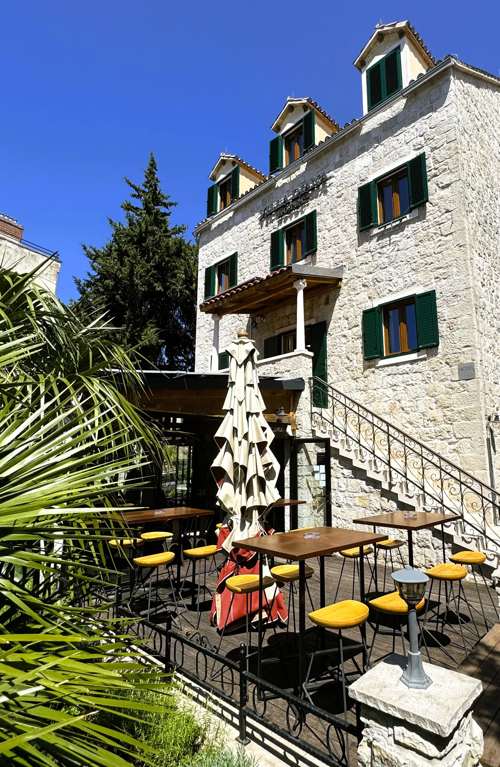 The terrace with its tables and parasol below the stone façade, by day, Pizzeria Villa Diana, Lučac, Split