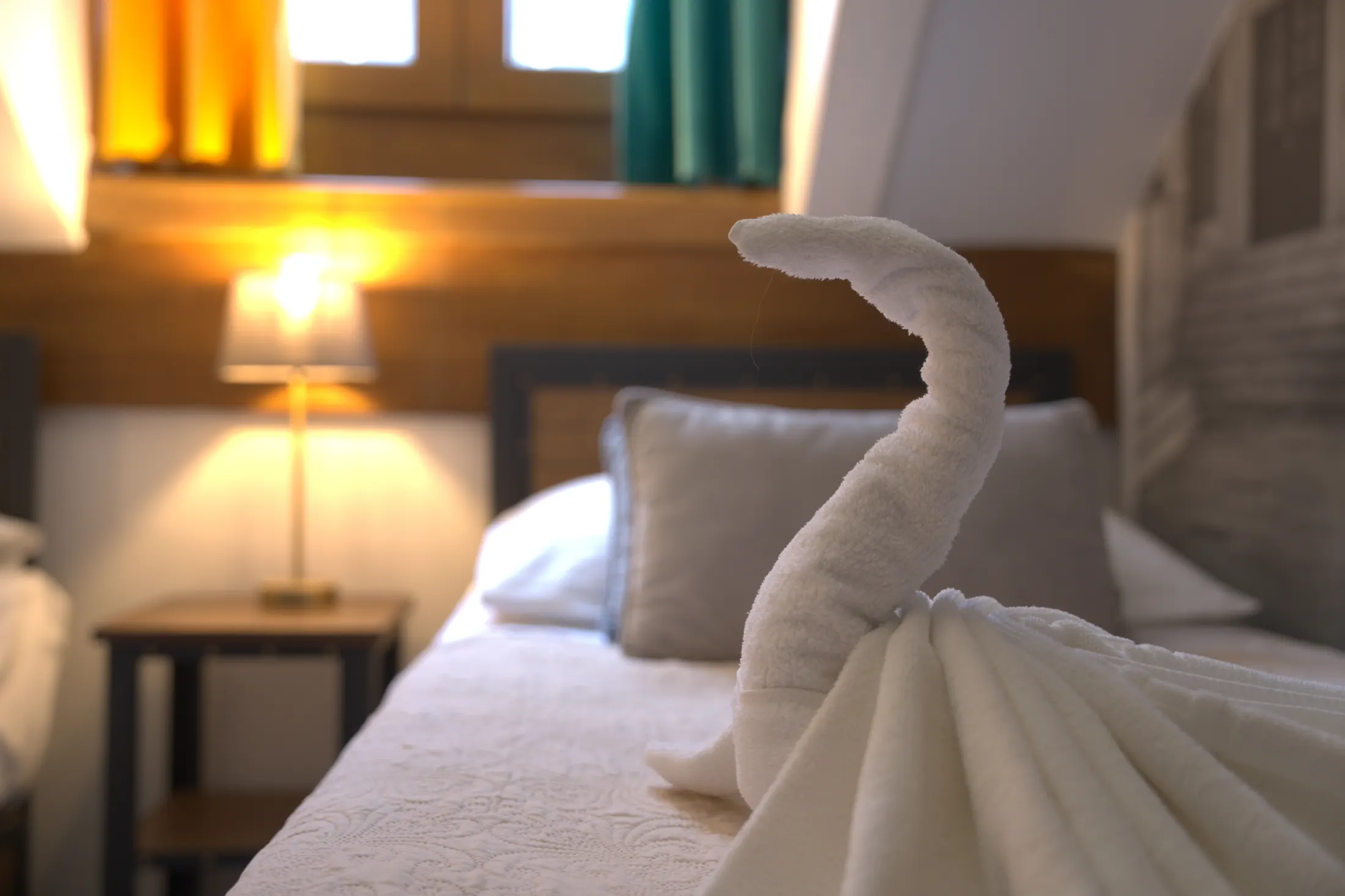 A towel folded into a swan on the bed, beside the reading lamp, Hotel Villa Diana, Lučac, Split