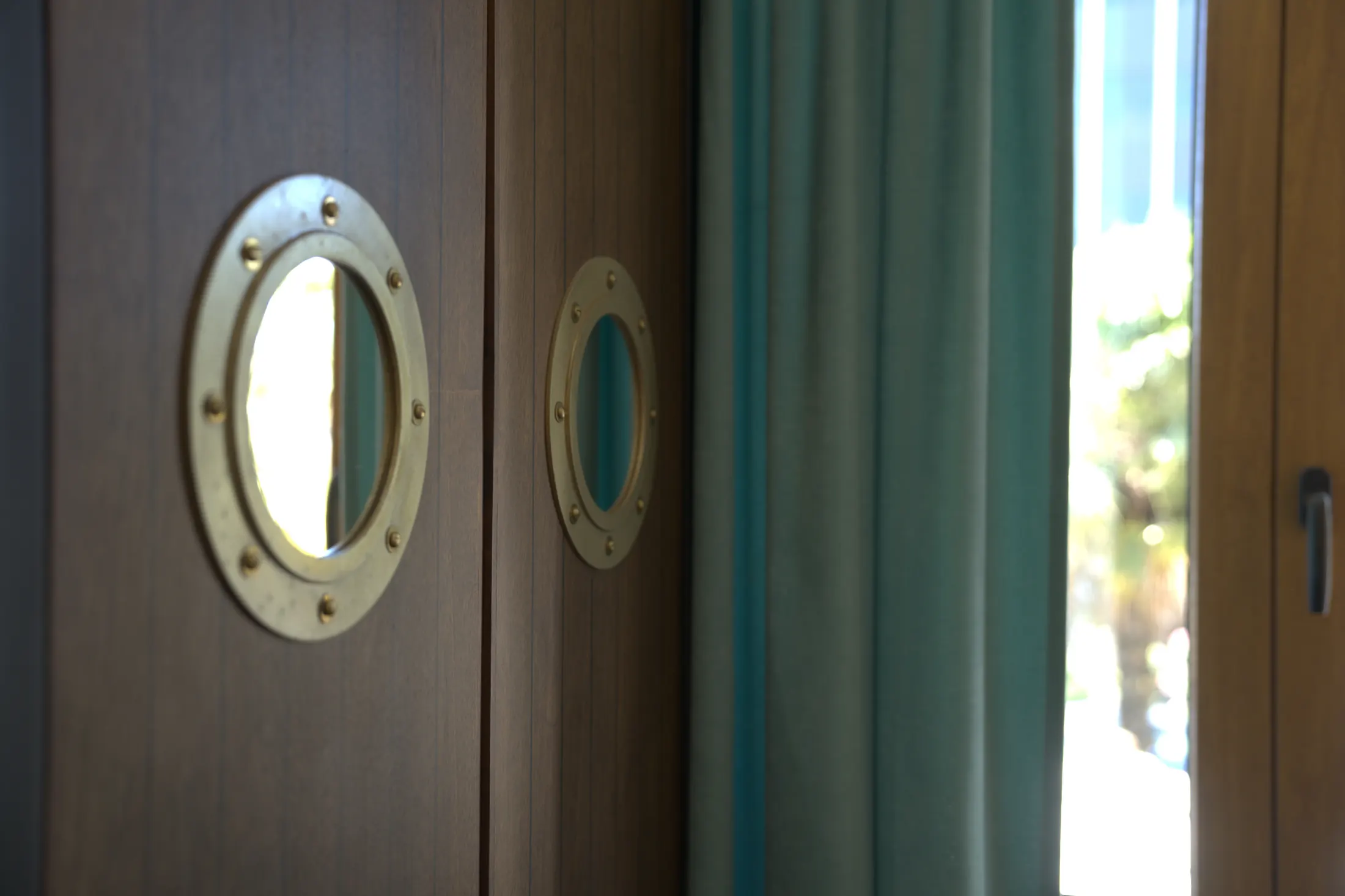 The wardrobe with porthole windows, beside the curtained window, Hotel Villa Diana, Lučac, Split